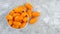 Small bowl overflowing with orange grape tomatoes on a gray marble background viewed from above