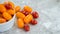 Small bowl overflowing with red and orange grape tomatoes on a gray marble background