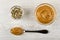 Small bowl with sesame, sunflower seeds, pumpkin seeds, transparent bowl with peanut butter, spoon with peanut butter on wooden