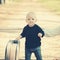 Small boy carry retro suitcase on natural landscape. Child travel for vacation with bag with mothers hand. Kid traveler