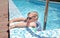 Small boy clambering out swimming pool