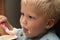 Small boy eating yogurt with red spoon detail