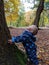 A small boy gazes up the trunk of a tree