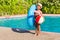 Small boy with inflatable ring, ball, pool noodle