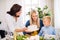 A small boy with mother looking at grandmother putting a cake on table at Christmas time.