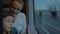 Small boy with mother sitting against window in their rail train place and watching outside