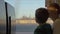 Small boy with mother sitting against window in their rail train place and watching outside on freight trains