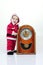 Small boy in Santa suit plays with vintage clock in white studio