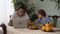 Small boy sitting on the kitchen table eating croissant with cappuccino and older adult brother watching laptop computer