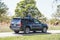 .Small boy standing in sunroof of SUV driving through wildlife park with blurred bison grazing among