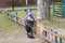 A small boy of three years old on a cool spring sunny day is trying to open a small wooden fence to go to the playground of the