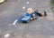 A small boy of three years old is lying on the pavement near the kindergarten with his toy truck