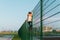 A small boy in warm clothes climbs a metal fence