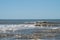 Small breaking waves on a beach with dark brown ocean water.