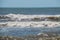 Small breaking waves on a beach with dark brown ocean water.