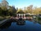 small bridge crosses over a small pond in a park with a gazebo