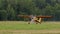 small bright yellow-red civilian small aircraft accelerates across field and is ready to take off. propeller plane on