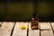 Small brown medicine bottle for magicians remedy, yellow flower lying next to it, sitting on wooden surface