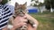 A small brown one-eyed kitten disabled sits in the arms of a woman.