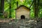 Small brown wooden hedgehog house on the lush green forest ground