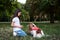Small brunette girl with Cavalier king charles spaniel, training in park in summer. Girl, wearing blue jeans and white t-shirt,