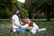 Small brunette girl with Cavalier king charles spaniel, training in park in summer. Girl, wearing blue jeans and white t-shirt,