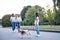 Small brunette girl,wearing blue jeans and white shirt holding white and brown dog in city park in summer with two women at the