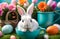 A small bunny in a cup, surrounded by flowers and Easter eggs.