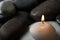 Small burning candle on beautiful spa stones