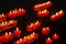 small burning church candles in red glass candleholders photographed diagonally on the chandelier