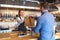 Small business and entrepreneur concept with smiling young waitress wearing black apron serving customer at counter in restaurant