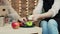 Small business owner cutting apples to give sample to cheerful clients