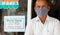 Small business owner in medical mask standing in front of door with we are open wear mask notice board - concept of support local