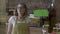 Small business owner wearing apron flipping over green screen sign on the door smiling and waiting for customers to come in -