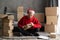 Small business owner working in home office with delivery boxes sitting on the floor. man in a santa hat sticking a