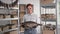 small business, portrait of young smiling woman with big salted fish in her hands stands in warehouse and looks around