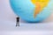 Small businessman figures standing on turning point on earth background.