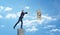 A small businessman standing on a concrete column and catching a dollar bill caught on a metal hook.