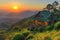 A small cabin on a hillside overlooking the sunset, AI