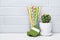 Small cactus in white flower pot, green gift box and colorful cocktail straws in glass as attributes of party