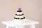 Small cake on three floors decorated mulberry and purple macaroon on top.