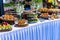 Small cakes, fruit, shrimp skewers and decorations on the white table