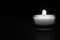 Small candle in glass with burning flame black and white monochrome.