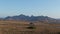 A small car rides on the road against the backdrop of the mountains.