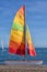 Small catamaran dinghy with brightly coloured sails. Torre Del Mar, Spain.