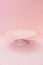 Small ceramic empty pink pedestal cake stand on a pastel pink table