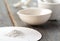 Small ceramic mortar, bowl and pestle with white powder on wooden background.