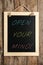 Small chalkboard with motivational quote Open your mind hanging on wooden wall