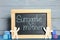 Small chalkboard with phrase Surrogate mother, people figures and cubes on blue wooden table
