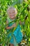 A small, cheerful girl among high, green corn